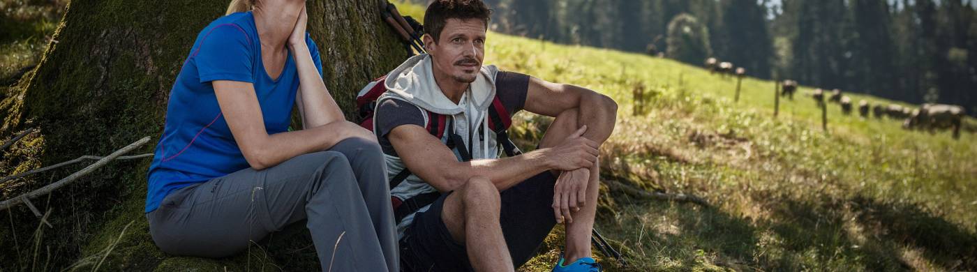 Paar ruht sich vom Wandern unter einer Tanne aus