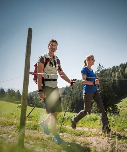 Mann und Frau beim Spazieren mit Stöcken in Österreich