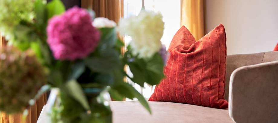 Bunte Hortensien in Vase mit Couch und Kissen im Hintergrund
