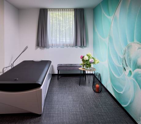 Massageliege mit Kerzen und Blumen